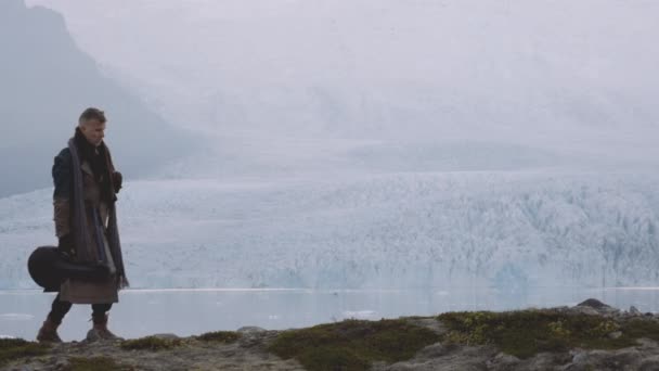 Человек, поднимающийся на холм рядом с ледником в Исландии — стоковое видео