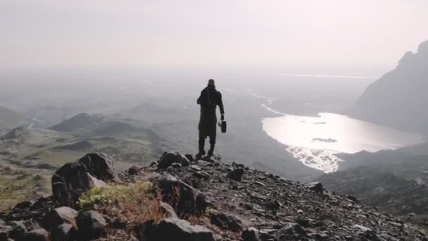 Drone over de mens wandelen naar Valley Edge om naar beneden te kijken in het landschap — Stockvideo