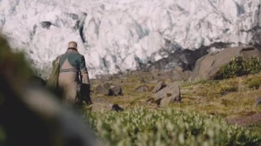 Buzulun yanındaki Rocky Hill 'de gitar çantası taşıyan gezgin.
