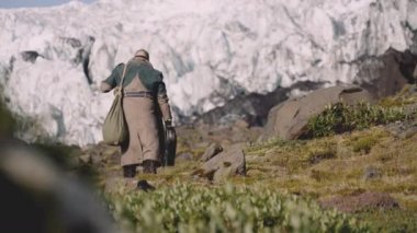 Buzulun yanındaki Rocky Hill 'de gitar çantası taşıyan gezgin.