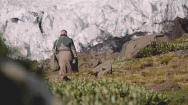 Buzulun yanındaki Rocky Hill 'de gitar çantası taşıyan gezgin.