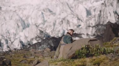Buzulun yanındaki Rocky Hill 'de gitar çantası taşıyan gezgin.