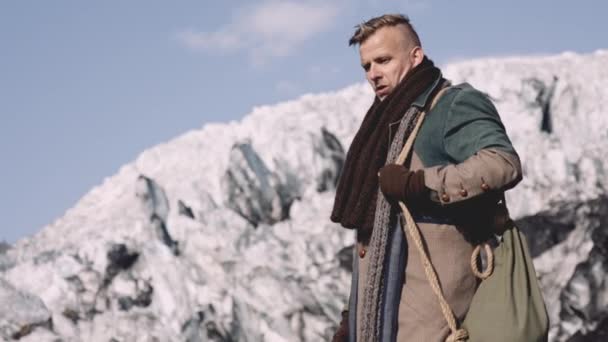 Man in grote jas loopt onder heldere blauwe lucht — Stockvideo