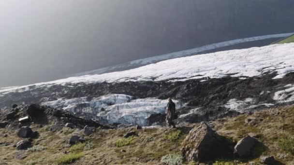 Cestující muž kráčí po hřebeni přes ledovec a údolí — Stock video