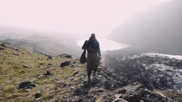 Man loopt langs Ridge naar op zoek naar Sunlit Valley — Stockvideo