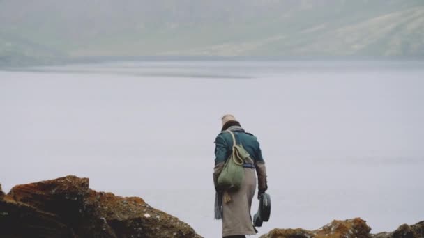 Lone Traveller wandelen naar beneden Rock By Lake — Stockvideo
