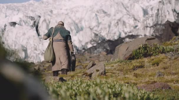 Reisender trägt Gitarrenkoffer auf Rocky Hill neben Gletscher — Stockvideo