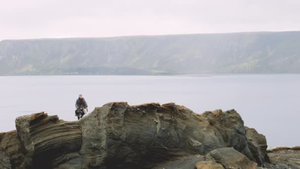 Viajero solitario trekking hasta roca al lado del lago — Vídeos de Stock