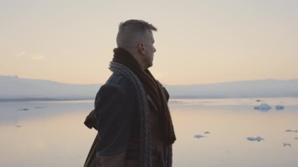 Hombre viajero con ropa abrigada mirando a su alrededor Paisaje islandés frío — Vídeo de stock