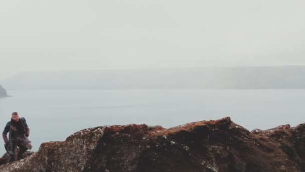 アイスランドの風景の中でロックをハイキングするギターを持つ孤独な男 — ストック動画