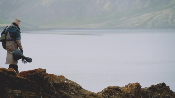 Reisender Mann mit Gitarre auf Rock in isländischer Landschaft — Stockvideo