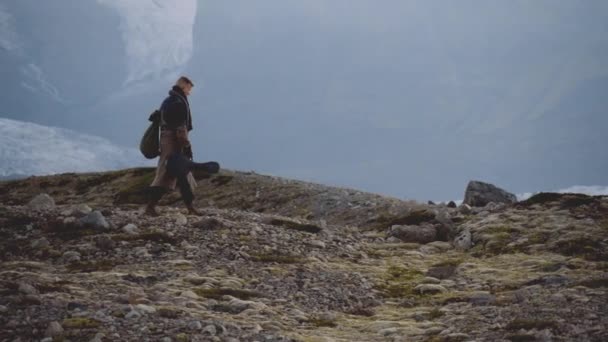 Viajando homem carregando guitarra e caminhadas sobre paisagem rochosa — Vídeo de Stock