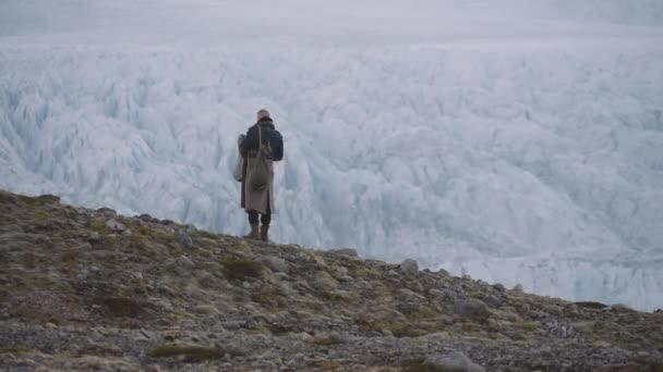Reizende man staand in rotsachtig landschap met gletsjer — Stockvideo