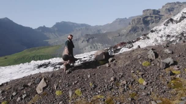 ギターケースと一緒に山の中腹を歩くハイカー — ストック動画