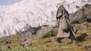 Buzulun yanındaki Rocky Hill 'de gitar çantası taşıyan gezgin.