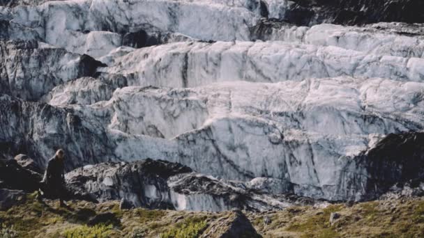 Reiziger loopt met gitaar geval langs Rocky Ridge naast gletsjer — Stockvideo