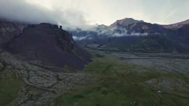 İnsansız hava aracı dağlarla ve alçak bulutlarla arazide uçuyor.