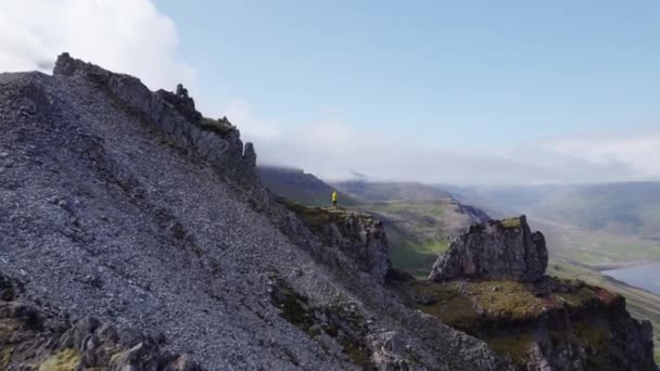 Полет дрона к человеку, стоящему на вершине горы — стоковое видео
