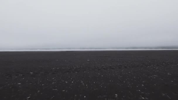 Drone vlucht over zwart zandstrand naar mistige zee — Stockvideo