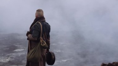 Greatcoat 'lu Adam Puslu ve Rocky Manzaralı Duruyor