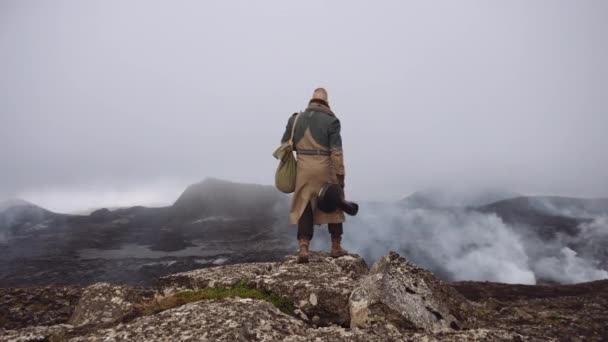 Reisender Mann trägt Gitarrenkoffer und geht zu nebligen Felsen — Stockvideo