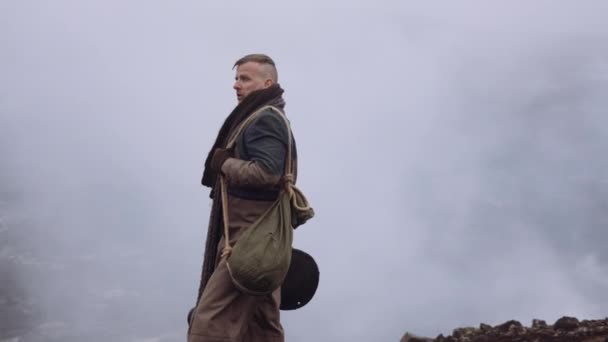 Muž ve velkém plášti stojící v mlhavé a skalnaté krajině — Stock video