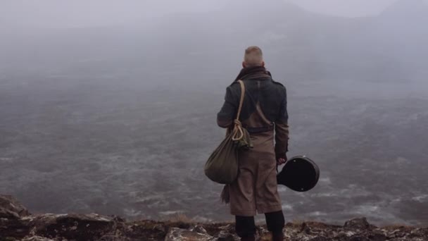 Mann in dickem Mantel steht in nebliger und felsiger Landschaft — Stockvideo