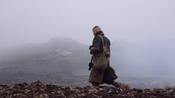 Homem viajante transportando caixa de guitarra andando sobre rochas enevoadas — Vídeo de Stock