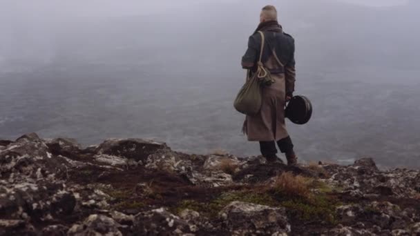 Uomo in grande cappotto in piedi in nebbioso e roccioso paesaggio — Video Stock