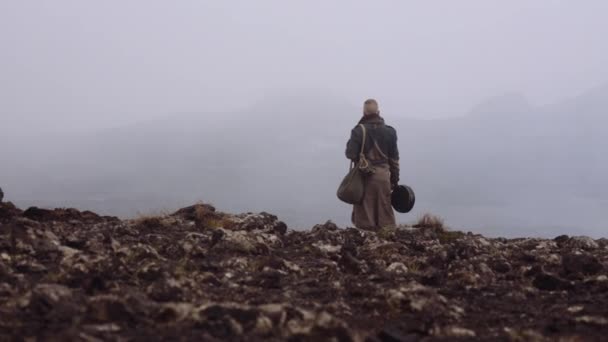 Muž ve velkém plášti stojící v mlhavé a skalnaté krajině — Stock video