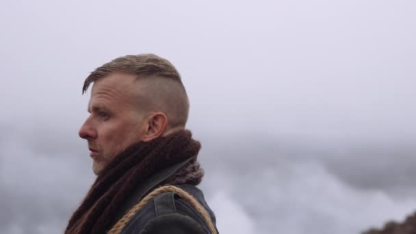 Człowiek w wielkim płaszczu stojący w mglistym i skalistym krajobrazie — Wideo stockowe