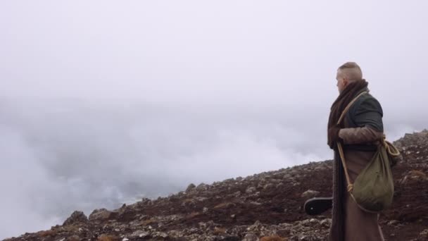 Uomo in grande cappotto in piedi in nebbioso e roccioso paesaggio — Video Stock