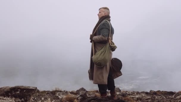 Man met grote jas staand in mistig en rotsachtig landschap — Stockvideo