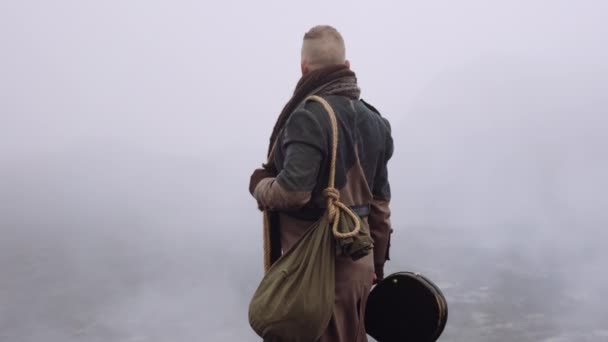 Homme en grand manteau debout dans un paysage brumeux et rocheux — Video
