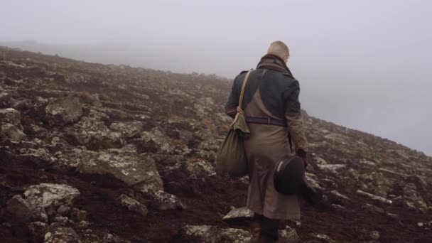 Uomo in grande cappotto a piedi attraverso nebbioso e roccioso paesaggio — Video Stock