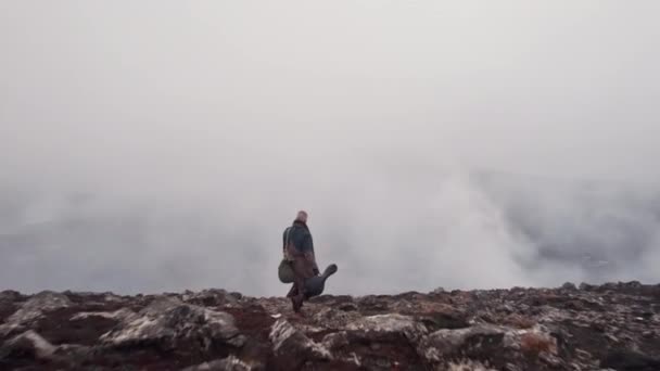Drönare av människan i stor rock vandrar genom dimmiga landskap — Stockvideo