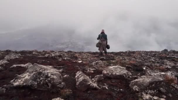 Drönare av människan i stor rock står genom dimmiga landskap — Stockvideo