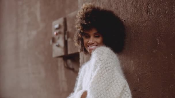 穿着羊毛衫、脚后跟高的带着风吹来的非洲人微笑的女人 — 图库视频影像