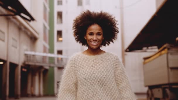 Mujer joven sonriente con cabello afro caminando hacia la cámara — Vídeos de Stock