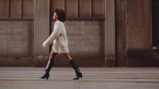 Leende ung kvinna med vindpinad afro hår promenader längs gatan — Stockvideo