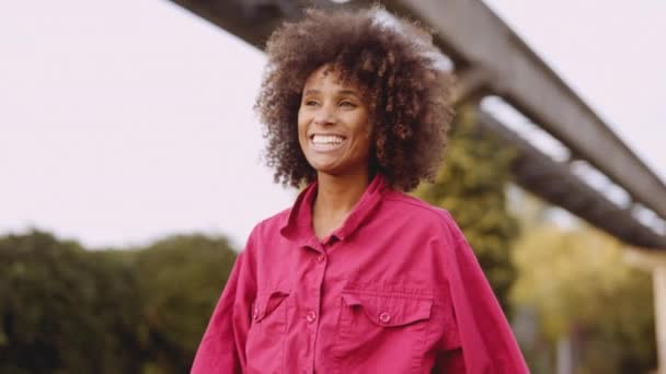 ยิ้ม ผู้หญิง กับ Afro ผม เดินไปตาม ใน สีชมพูสดใส ด้านบน — วีดีโอสต็อก