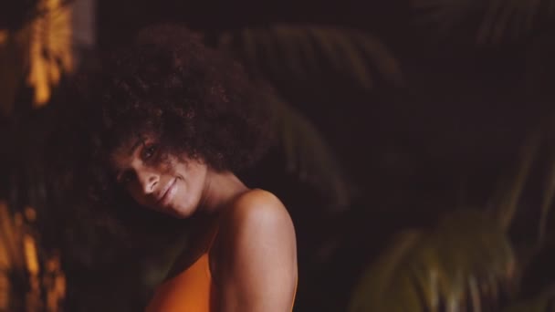 Glimlachende vrouw met Afro haar dansen om camera in oranje jurk — Stockvideo