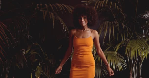 Hermosa joven mujer con afro en naranja vestido bailando a cámara — Vídeos de Stock