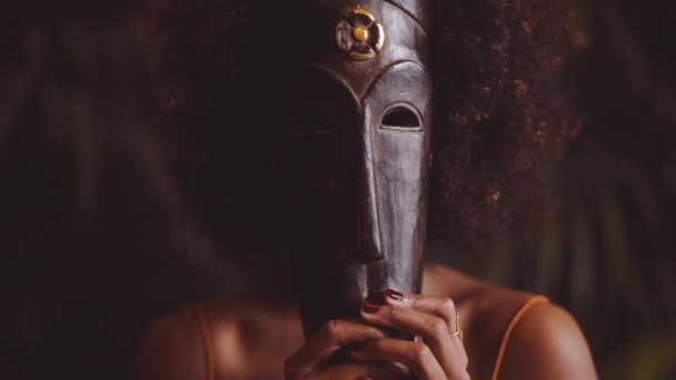 Vrouw met afro houden traditionele masker over gezicht — Stockvideo
