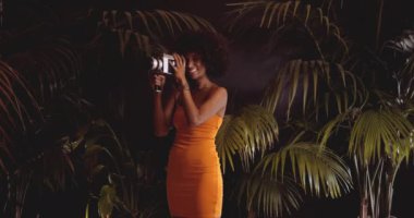 Turuncu Giysili Afro Saçlı Kadın Klasik Kamera Kullanıyor