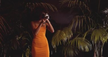 Turuncu Giysili Afro Saçlı Kadın Klasik Kamera Kullanıyor