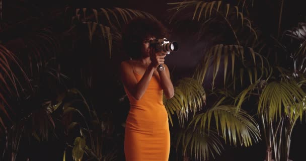 Afro saçlı, turuncu elbiseli, klasik 8Mm kameralı kadın. — Stok video