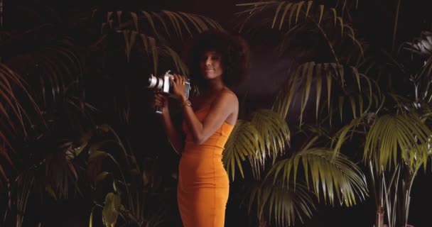 Kobieta z afro włosy w pomarańczowej sukience przy użyciu Vintage 8Mm aparat — Wideo stockowe