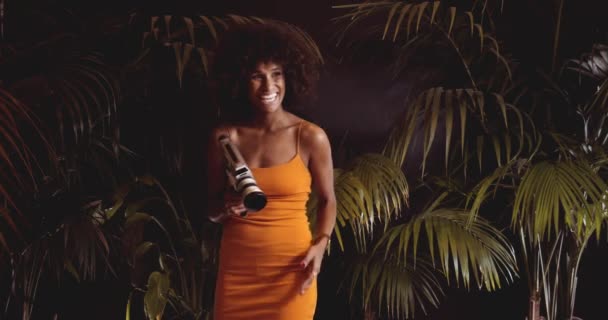 ヴィンテージ8mmカメラを使用したオレンジのドレスでアフロヘアの女性 — ストック動画