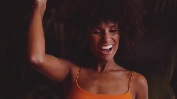 Жінка з афро волоссям в помаранчевій сукні Використовуючи вінтажну камеру 8Mm — стокове відео